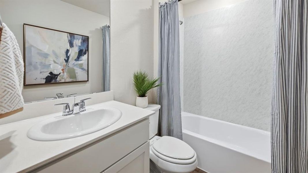 Bathroom featuring a white sink with chrome fixtures, a toilet, and a bathtub with a shower