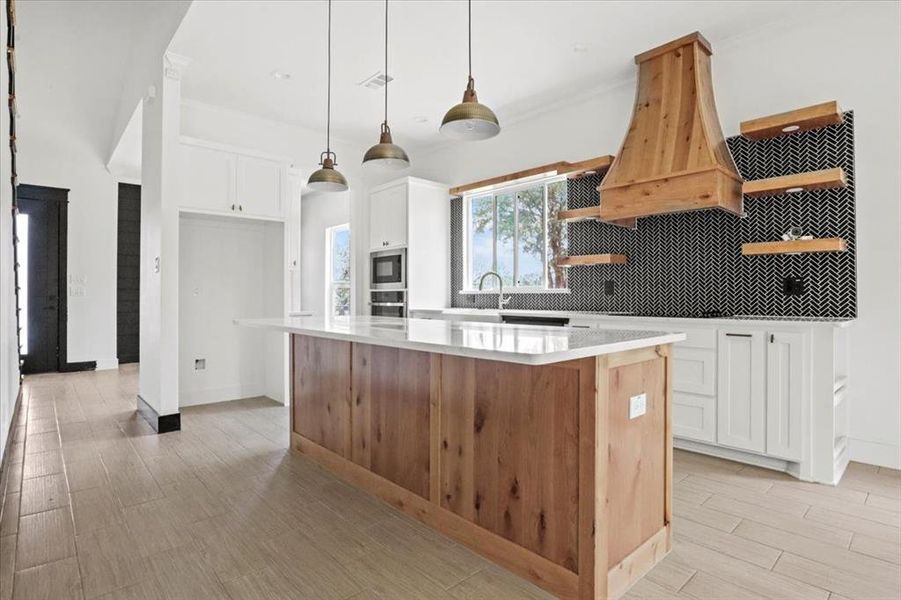 Kitchen featuring white cabinetry, open shelves, backsplash, wood tiled floors, and a kitchen island