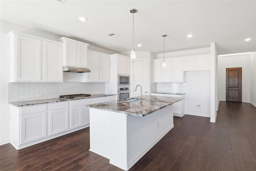 Modern kitchen featuring white shaker cabinetry and a large island with a stone countertop