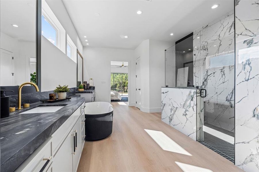 Full bathroom with plenty of natural light, a marble finish shower, recessed lighting, two vanities, and a freestanding tub