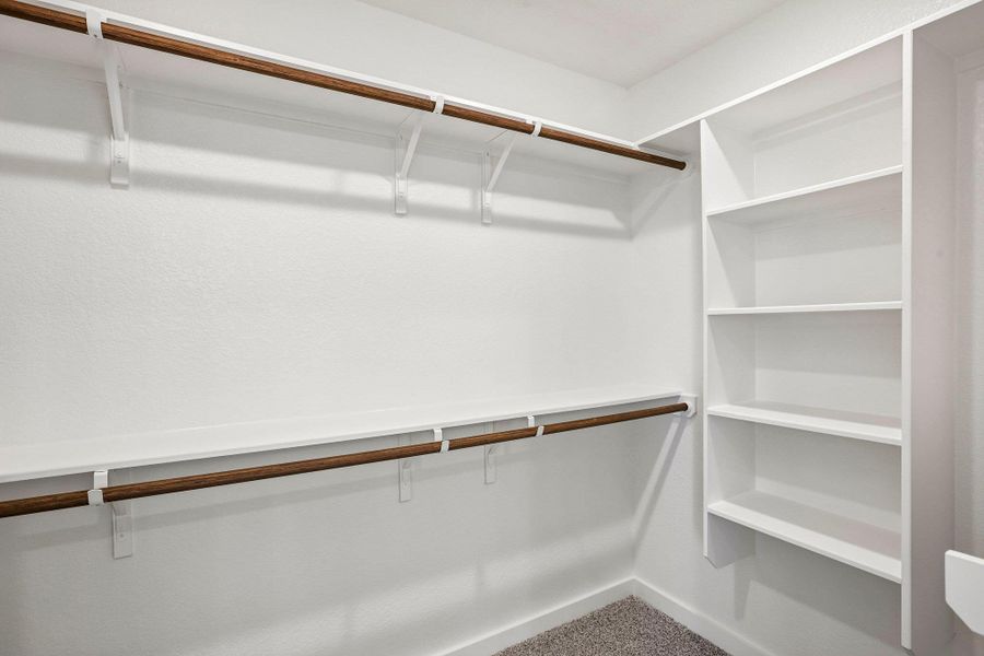 Ample built-in shelving and hanging rods maximize storage space within this walk-in closet.