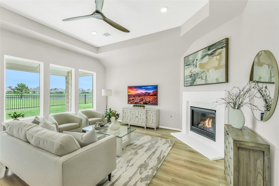 Spacious family room with custom gas fireplace, ceiling fan, and large low-E windows providing abundant natural light.
