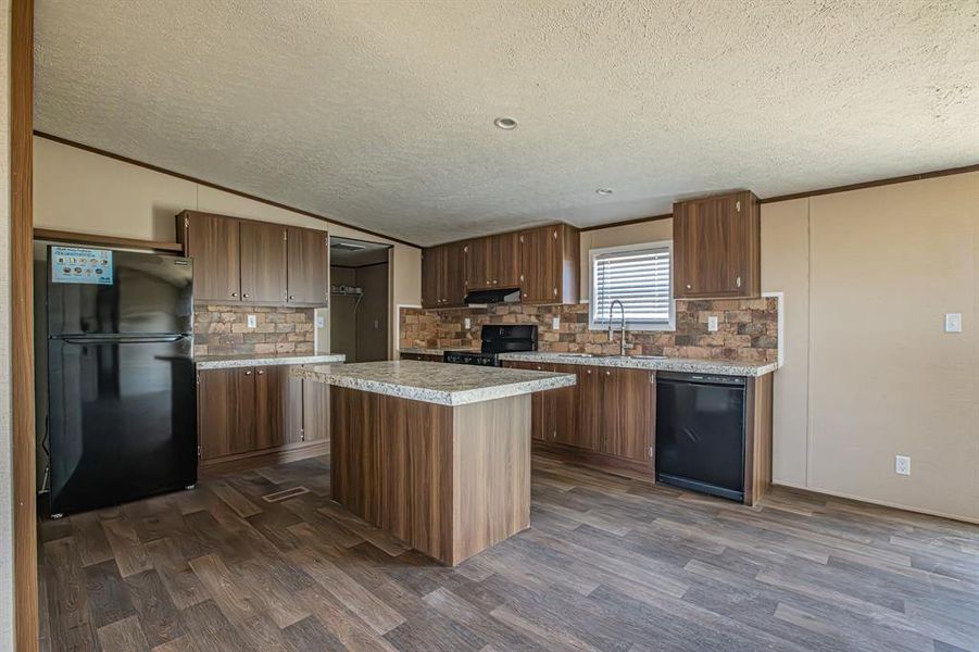 Kitchen featuring a center island, black appliances, sink and backsplash