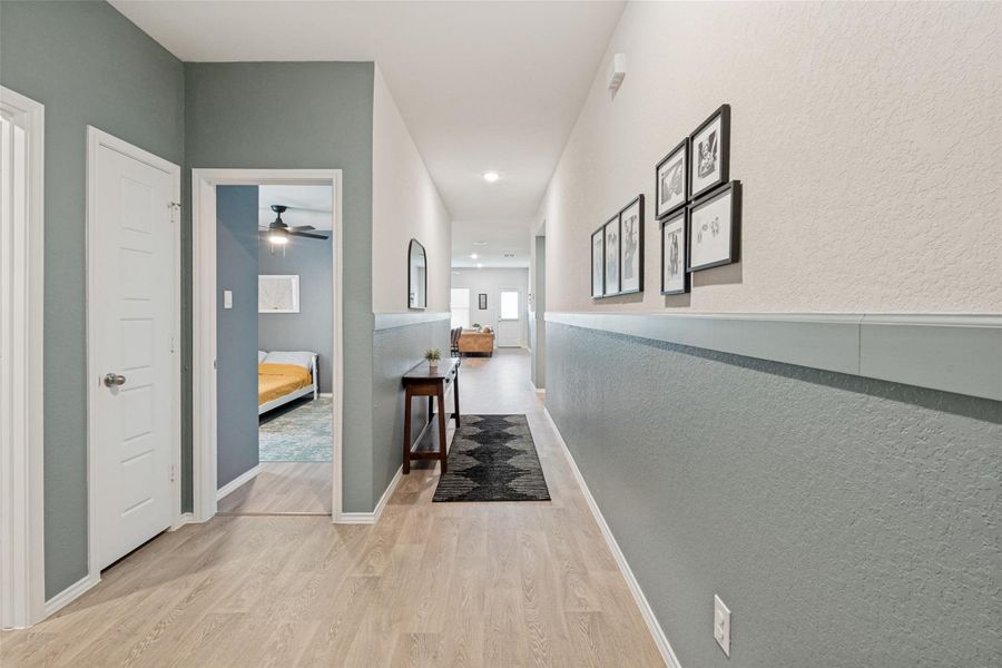 A well-lit hallway with natural wood-look flooring connects various rooms.
