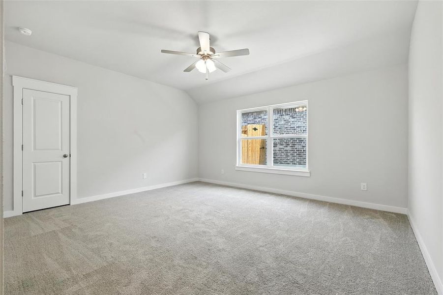 Empty room featuring carpet, a ceiling fan, and vaulted ceiling