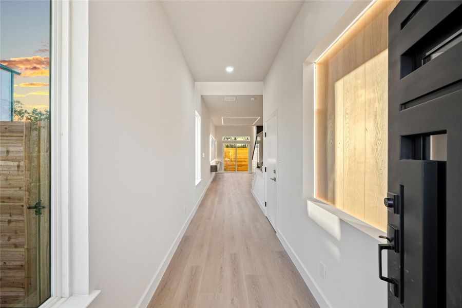 Corridor with light wood-style flooring and recessed lighting.