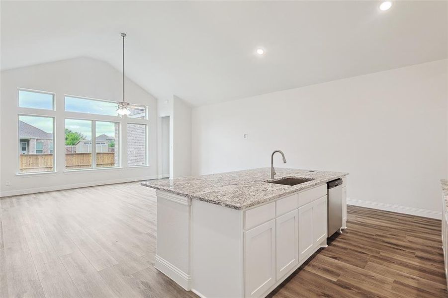 Kitchen with hardwood / wood-style floors, a center island with sink, sink, and white cabinets