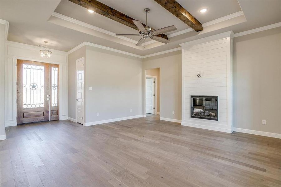 Unfurnished living room with crown molding, a fireplace, and light hardwood / wood-style flooring