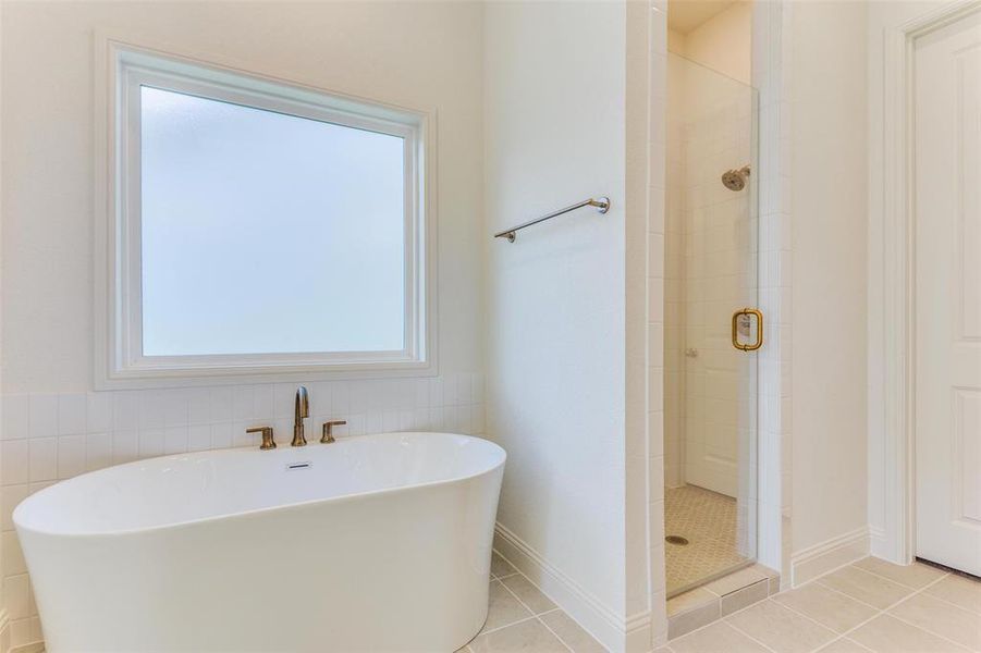 Bathroom featuring tile patterned flooring and shower with separate bathtub