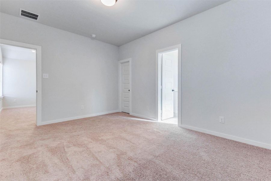One of three upstairs bedrooms, this secondary room includes direct access to a full en suite bathroom. Neutral carpeting, ample natural light, and walk-in closet space make this a cozy and private option for guests or family members.