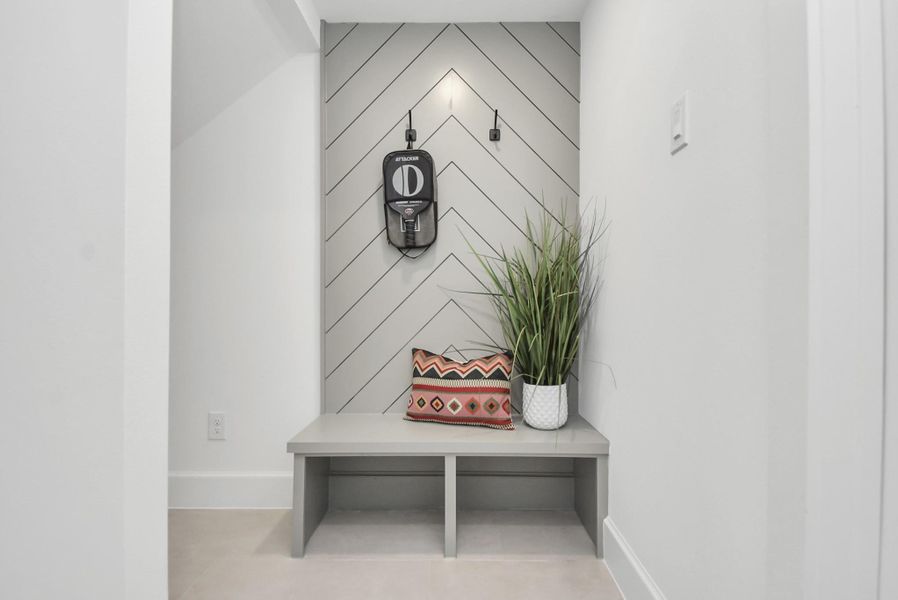 Step into this modern, minimalist nook featuring a sleek bench against chevron-patterned wall paneling. Accented with a decorative pillow and a potted plant, this space combines style and functionality, making it an inviting entryway or practical mudroom for everyday living. Step into this modern, minimalist nook featuring a sleek bench against chevron-patterned wall paneling. Accented with a decorative pillow and a potted plant, this space combines style and functionality, making it an inviting entryway or practical mudroom for everyday living.