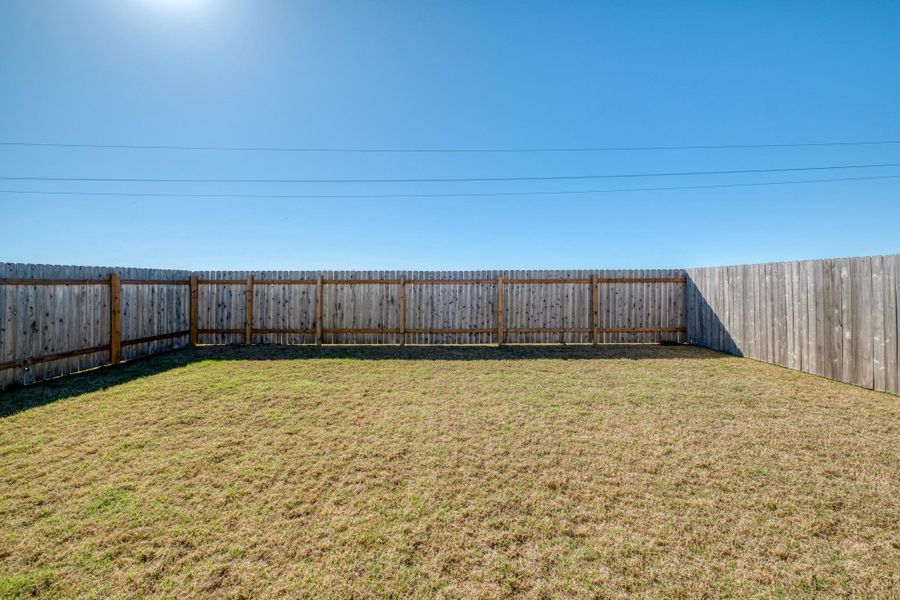 The property features an outdoor area with a wooden fence and a grassy lawn