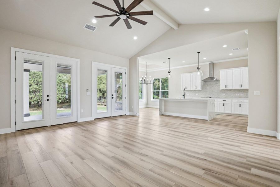 Unfurnished living room with beamed ceiling, a chandelier, recessed lighting, light wood-style flooring, and a ceiling fan