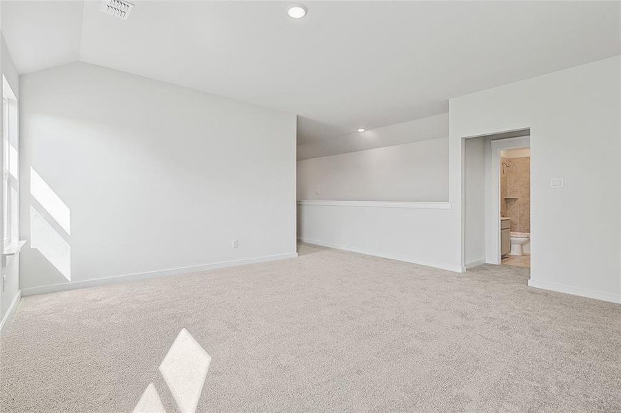 Carpeted empty room featuring vaulted ceiling