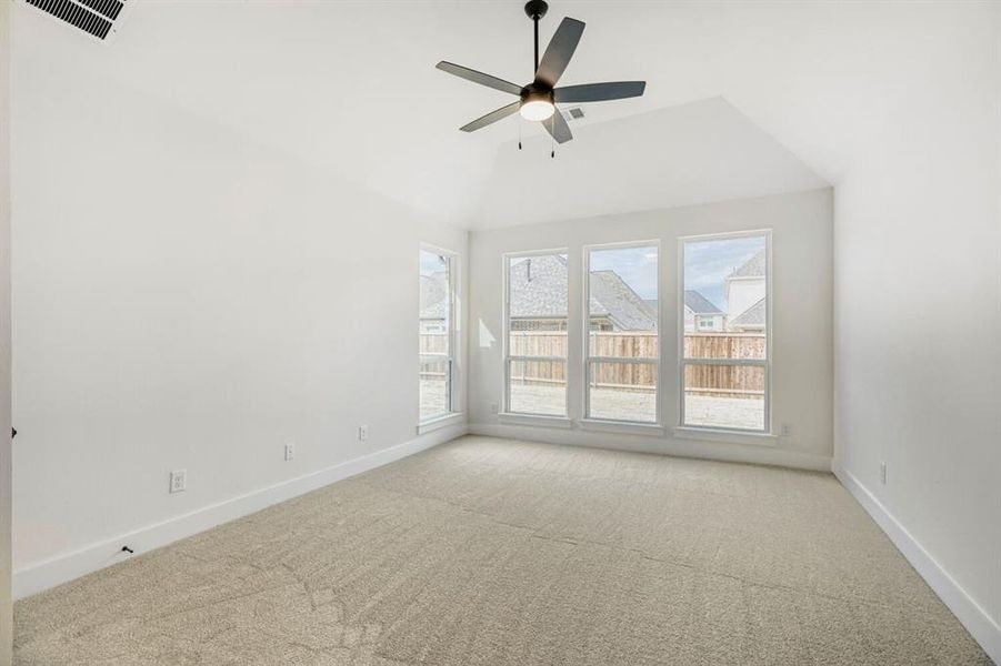 Spacious room featuring vaulted ceilings, a contemporary ceiling fan with integrated lighting, and plush carpet flooring