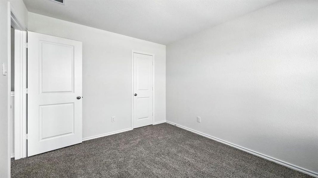 Neutral interior space featuring light-toned walls and dark gray carpeting