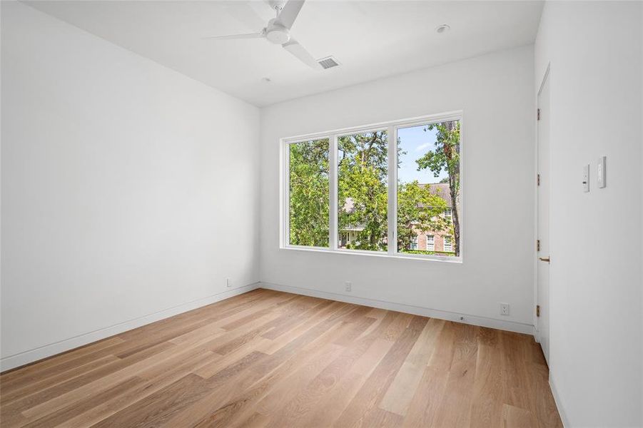 Offering beautiful treetop views, this serene secondary bedroom features luxurious 7-inch white oak hardwood floors, a spacious walk-in closet that provides ample storage, and an ensuite bath that adds both convenience and privacy.