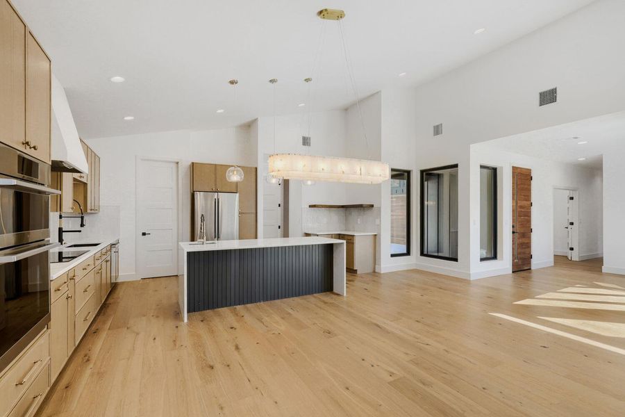 Kitchen with two tone cabinets, light wood finished floors, a kitchen island, stainless steel appliances, and vaulted ceiling Kitchen with two tone cabinets, light wood finished floors, a kitchen island, stainless steel appliances, and vaulted ceiling