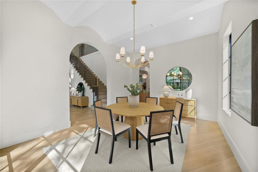 Dining area featuring an arched entryway, herringbone wood-finish flooring, and a modern chandelier