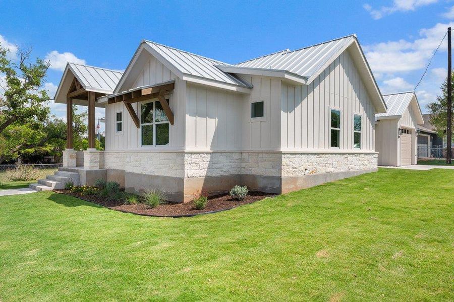 The property features a white board and batten exterior with a light-colored stone foundation and a metal roof