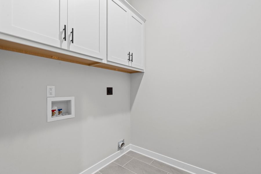 Washroom featuring cabinet space, light tile patterned floors, hookup for a washing machine, and electric dryer hookup Washroom featuring cabinet space, light tile patterned floors, hookup for a washing machine, and electric dryer hookup