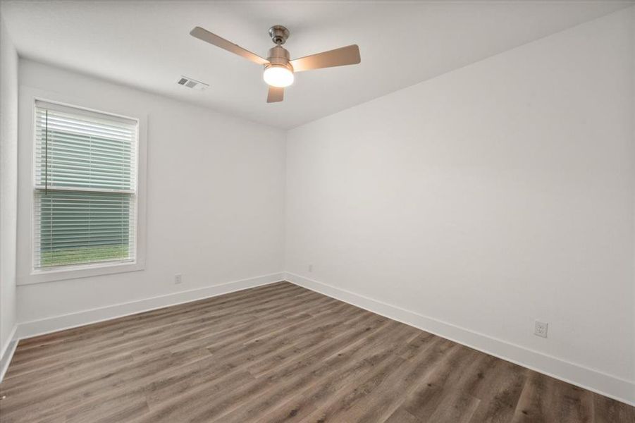 Bedroom with LVP wood-like flooring ceiling fan and nice double-door closet.