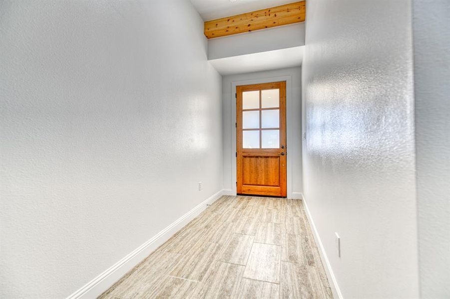 Doorway to outside with beam ceiling and light wood-type flooring