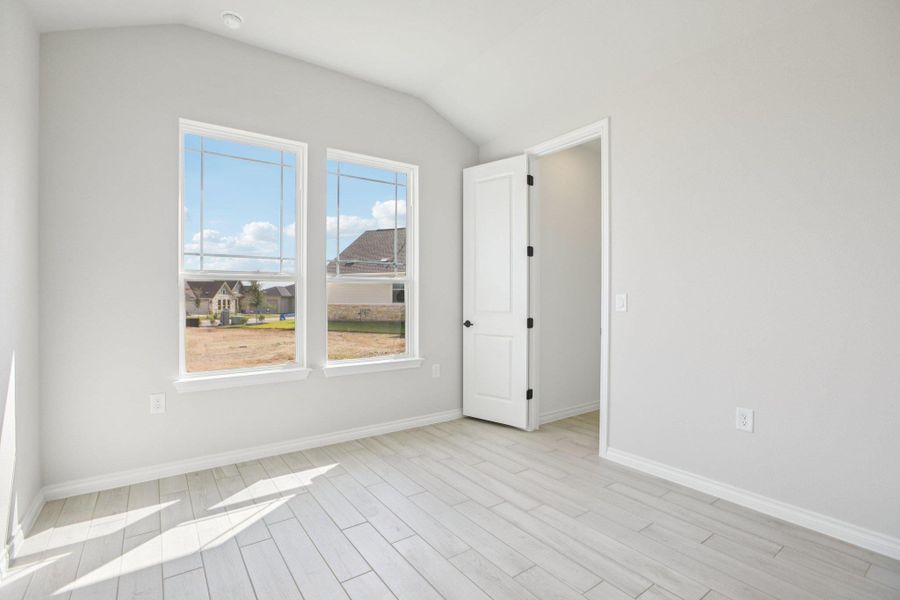 Empty room featuring vaulted ceiling and light wood-style floors