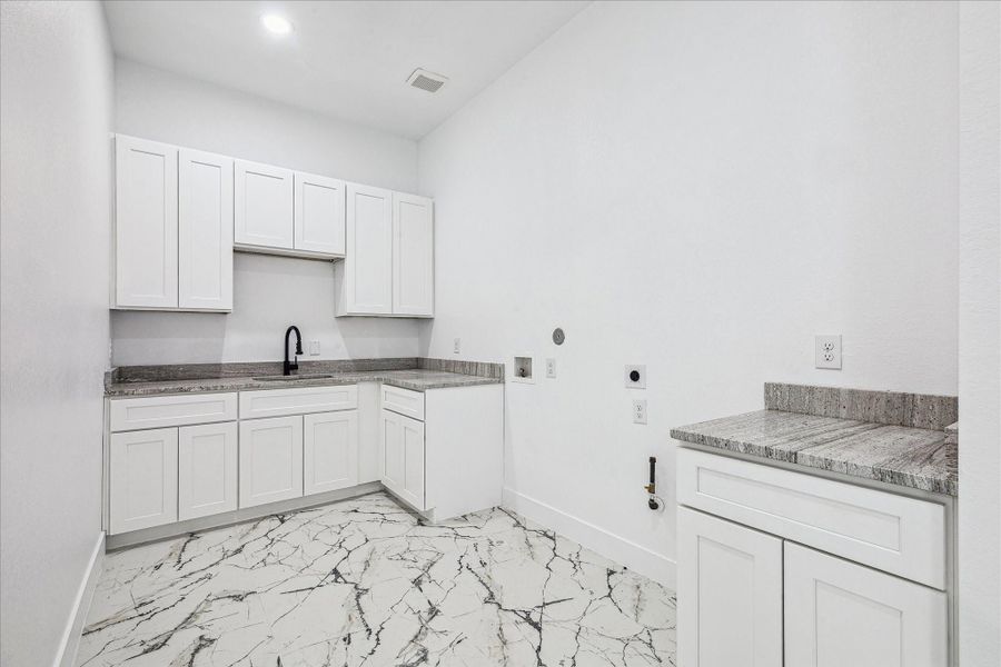 The oversized utility room offers gas or electric connections and features premium cabinetry, durable surfaces, and abundant room for all your laundry and storage needs.