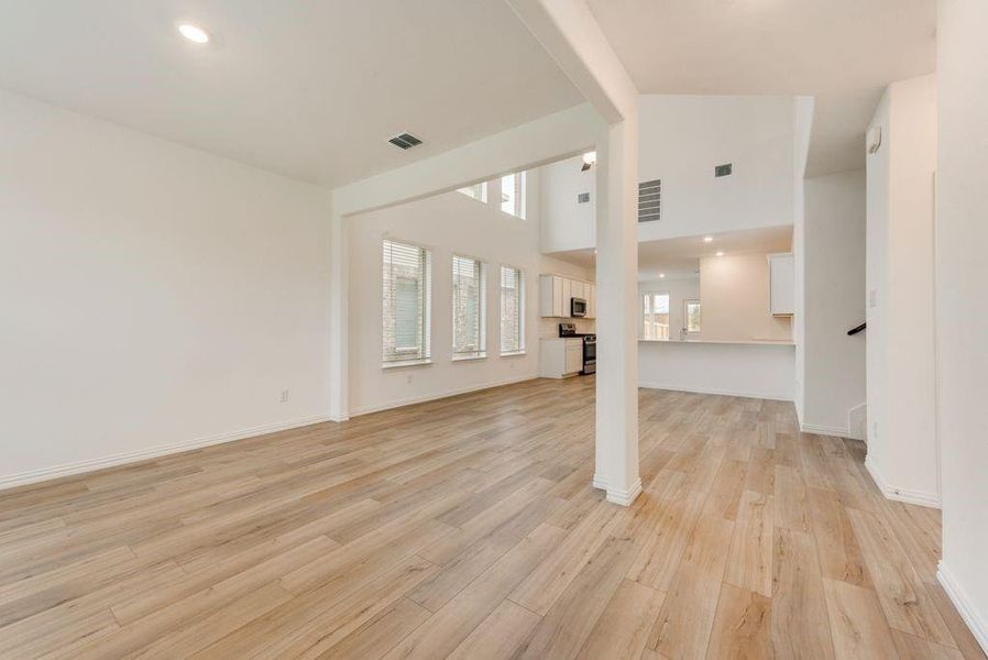 Unfurnished living room with light wood-type flooring and high vaulted ceiling