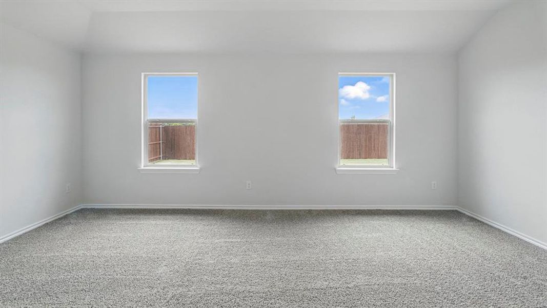 Spacious room featuring light gray wall paint, textured gray carpeting, white baseboards, and two rectangular windows with white trim
