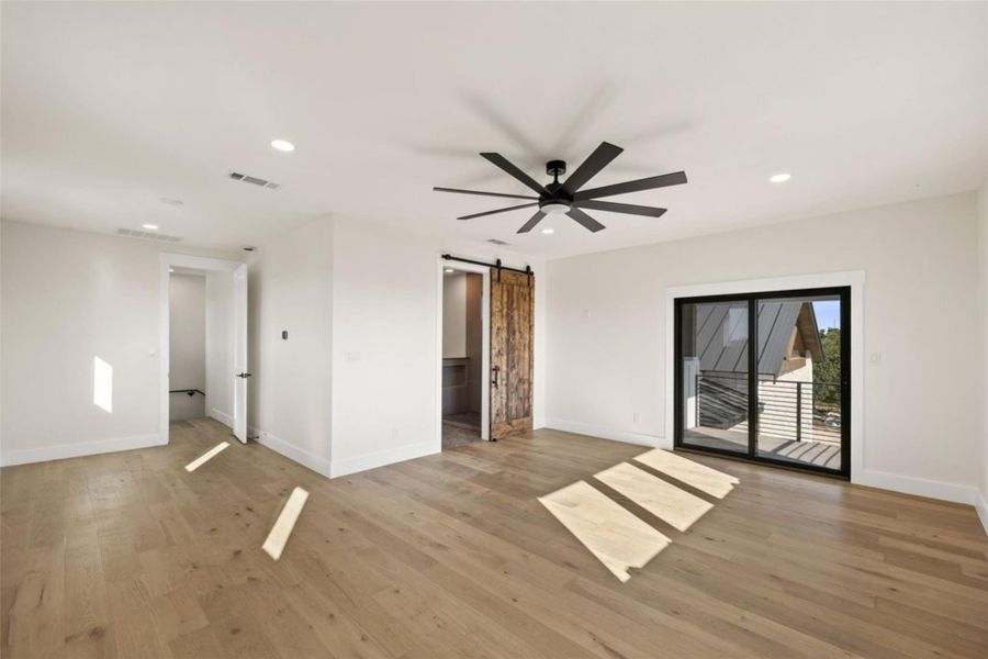 A spacious bedroom features light hardwood flooring, a ceiling fan, and sliding glass doors leading to a private balcony. A spacious bedroom features light hardwood flooring, a ceiling fan, and sliding glass doors leading to a private balcony.