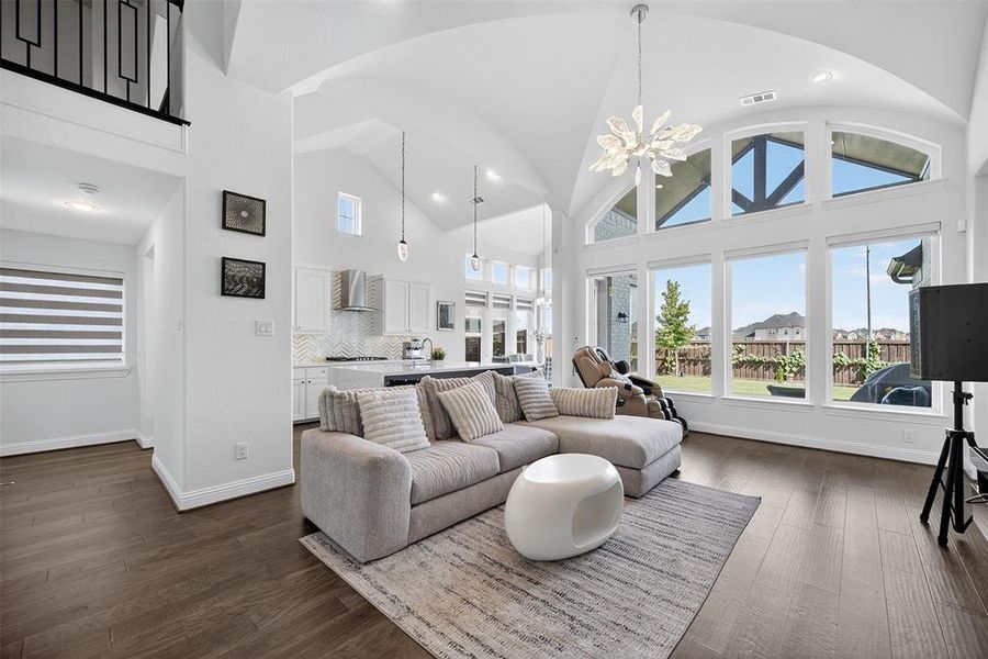 Living room featuring high vaulted ceiling, a chandelier, and dark wood-style floors Living room featuring high vaulted ceiling, a chandelier, and dark wood-style floors