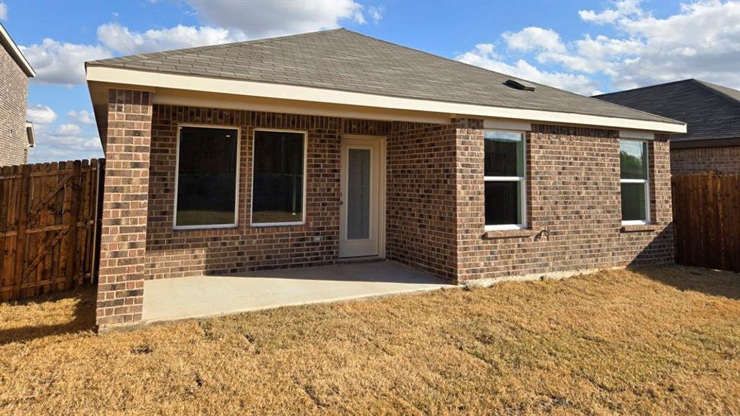 Back of property with a patio area, brick siding, and roof with shingles