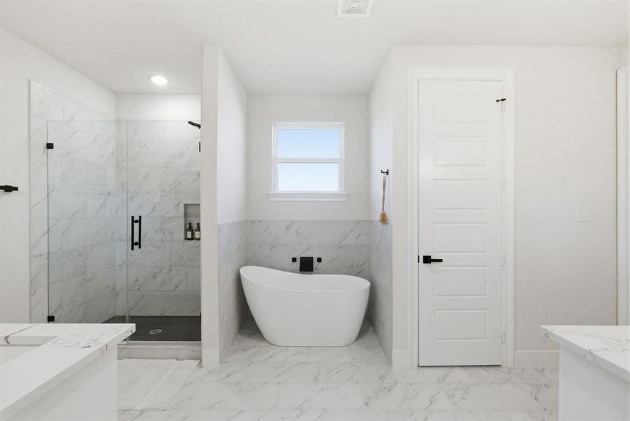 Full bath with vanity, a marble finish shower, light marble finish floors, a freestanding tub, and tile walls
