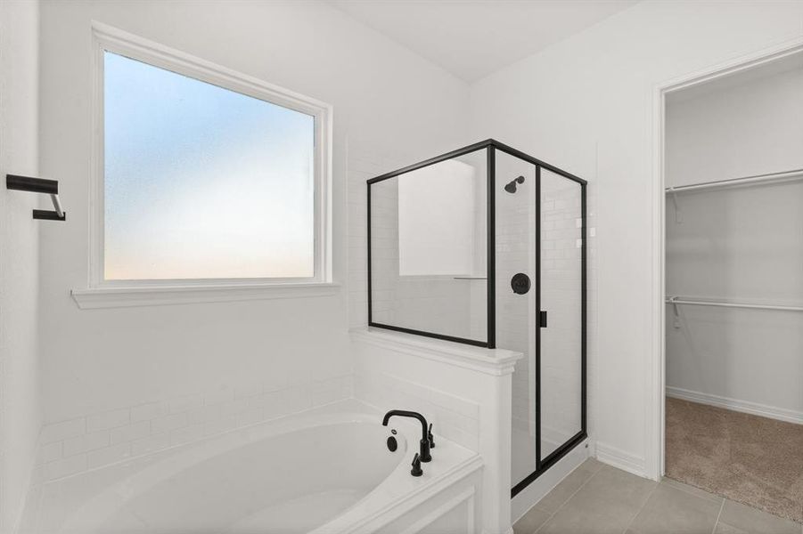 This additional view of your primary bathroom features tile flooring, fresh paint, walk-in shower, a separate garden tub, and a large walk-in closet.