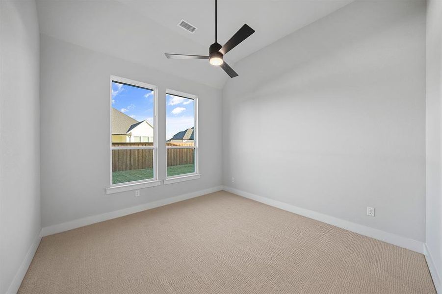 Carpeted empty room featuring lofted ceiling and a ceiling fan Carpeted empty room featuring lofted ceiling and a ceiling fan