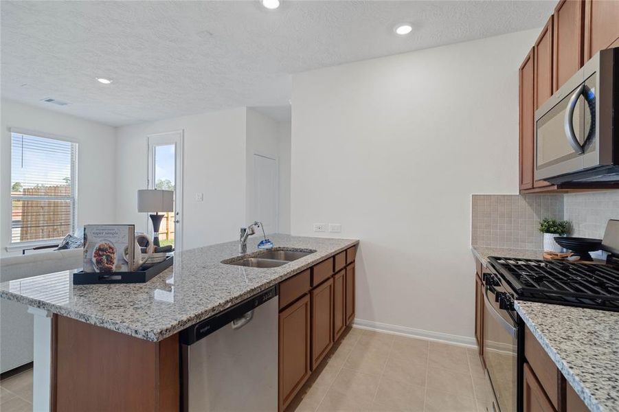 Additional view of this stunning kitchen! Featuring stained cabinets, granite countertops, modern backsplash, stainless steel appliances, recessed lighting, and custom paint.