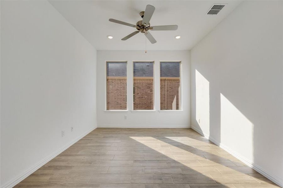 Empty room with ceiling fan and light hardwood / wood-style floors