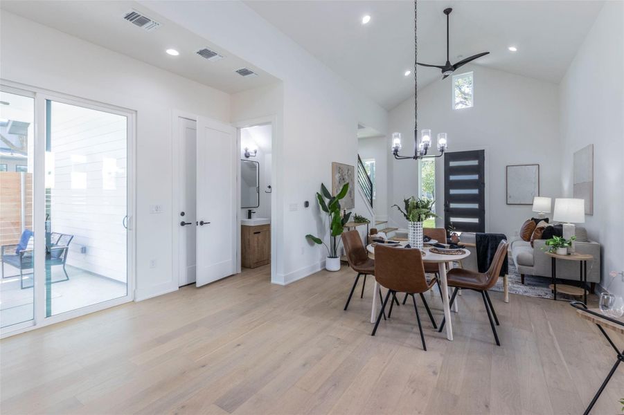Dining area with light wood-style flooring, high vaulted ceiling, and recessed lighting