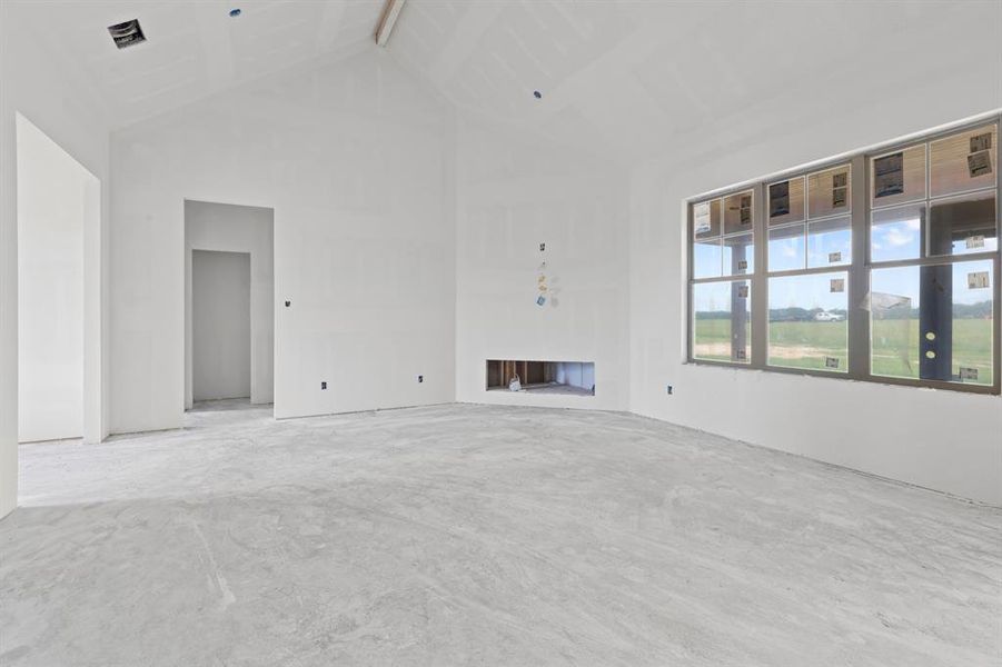 Spacious interior showcasing a vaulted ceiling, large multi-pane windows, and a recessed fireplace opening Spacious interior showcasing a vaulted ceiling, large multi-pane windows, and a recessed fireplace opening