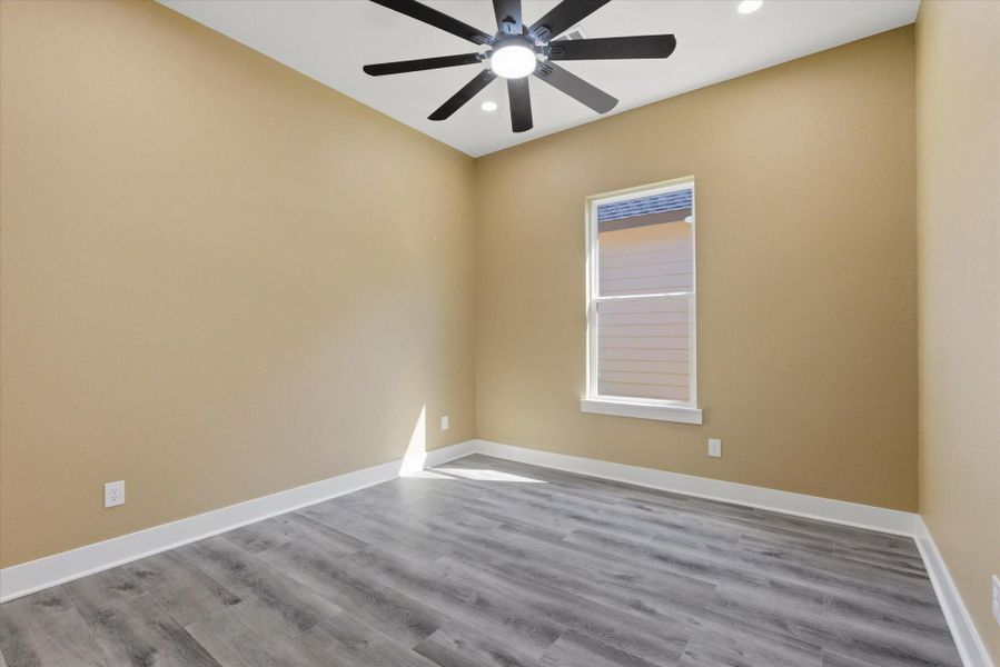 Secondary bedroom features recessed lighting, vinyl flooring, a ceiling fan for added comfort, warm brown tones, and a closet with built-in storage.