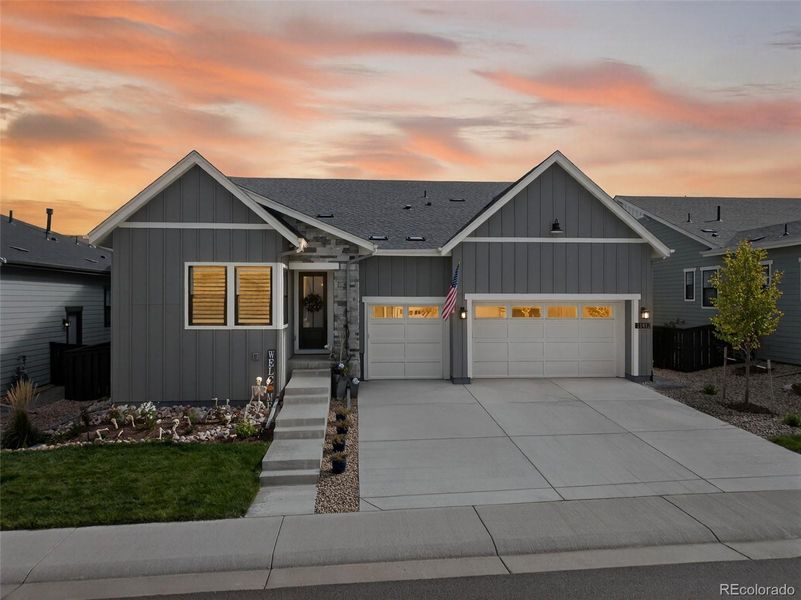 Front Exterior (Dusk) – Stunning modern ranch-style exterior with board-and-batten siding, stone accents, and a welcoming covered entry, beautifully highlighted by the warm glow of sunset.
