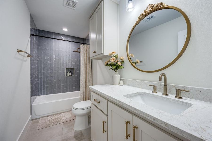 The first floor hallway bathroom features a generous vanity, tile shower / bath combination and flooring.