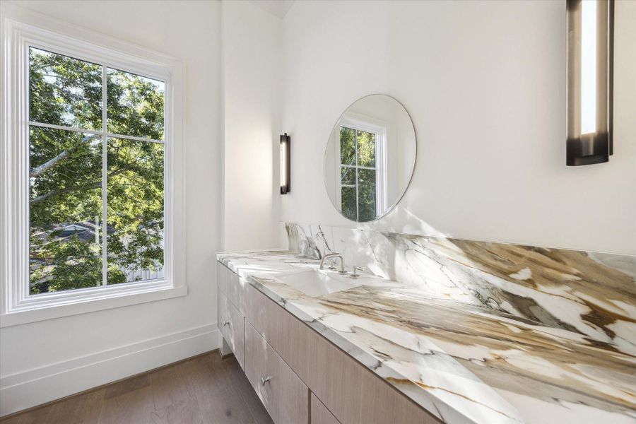 Second-floor powder room with a dramatic presence, featuring a marble countertop atop a floating vanity.