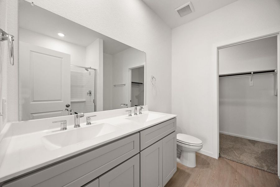 The primary bathroom features dual sinks, abundant counter space, modern finishes, and a functional layout designed to make busy mornings easier.