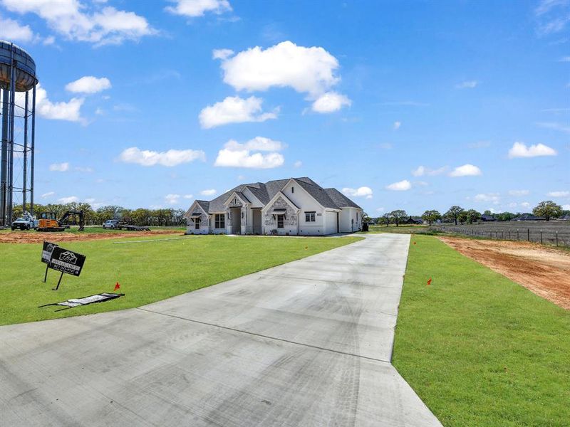 View of front of house featuring concrete driveway, a front lawn, stone siding, and an attached garage View of front of house featuring concrete driveway, a front lawn, stone siding, and an attached garage