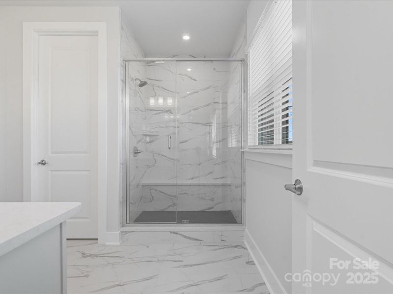En suite primary bath with modern marble look tile.