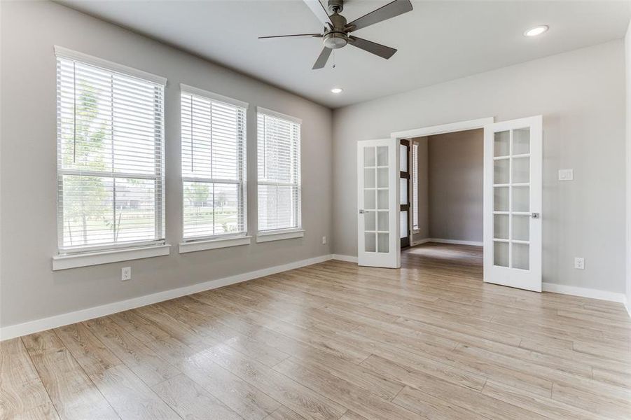 Empty room featuring ceiling fan, french doors, light hardwood / wood-style flooring, and plenty of natural light