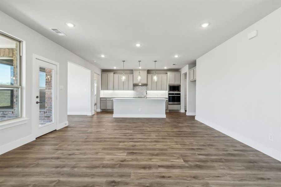 Unfurnished living room featuring dark hardwood / wood-style flooring, sink, and a healthy amount of sunlight